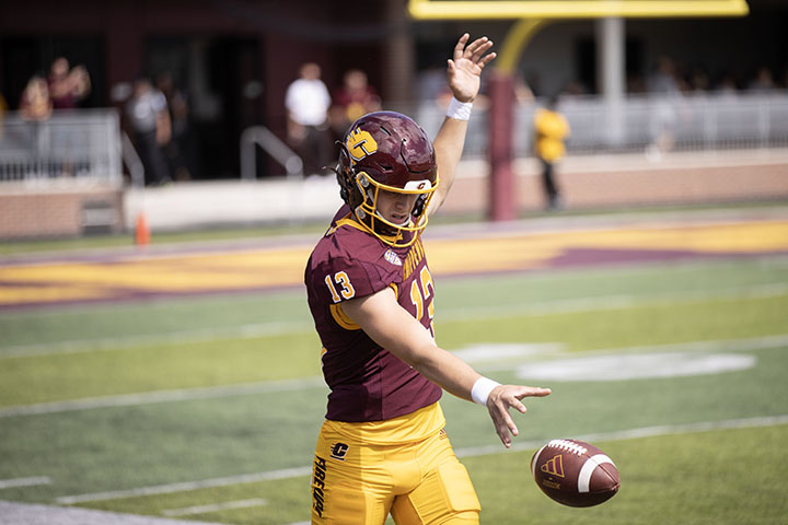 The CMU punter drops a football and prepares to kick it during the CMU-New Hampshire football game.