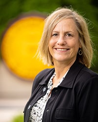 A woman wearing a black jacket smiles at the camera.