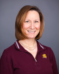 A woman wearing a maroon CMU polo shirt smiles at the camera.