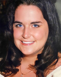 A caucasian woman with long black hair smiles at the camera.