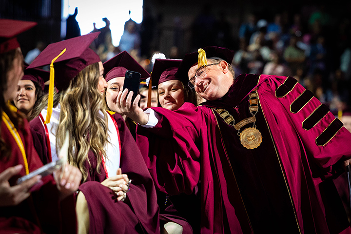 At CMU spring commencement, President Bob Davies takes a selfie with students waiting to receive their diplomas.