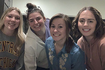 Four young women smile while posing for a group photo.