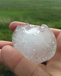 A palm-sized hail stone sits in a person's hand.