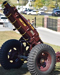A cannon painted with maroon paint points up into the air.
