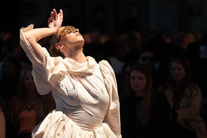 A CMU fashion student poses under a spotlight while wearing one of her designs.