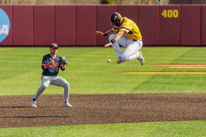 A CMU baseball player running from second base to third base jumps over a baseball as it bounces towards the shortstop.