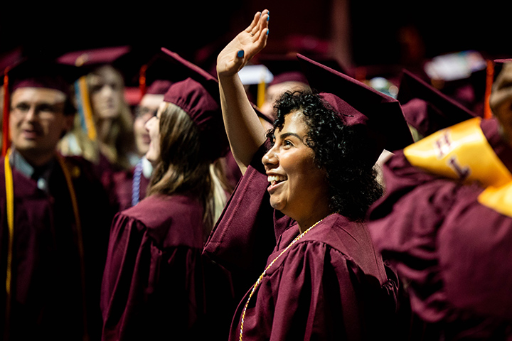 At CMU spring commencement, a graduate waves and smiles at the crowd.