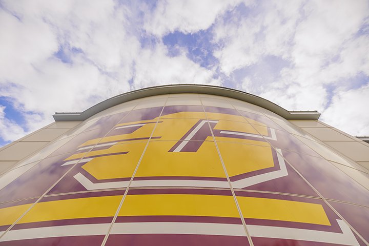 A low-angle view of a large CMU Action C logo on the side of a building.