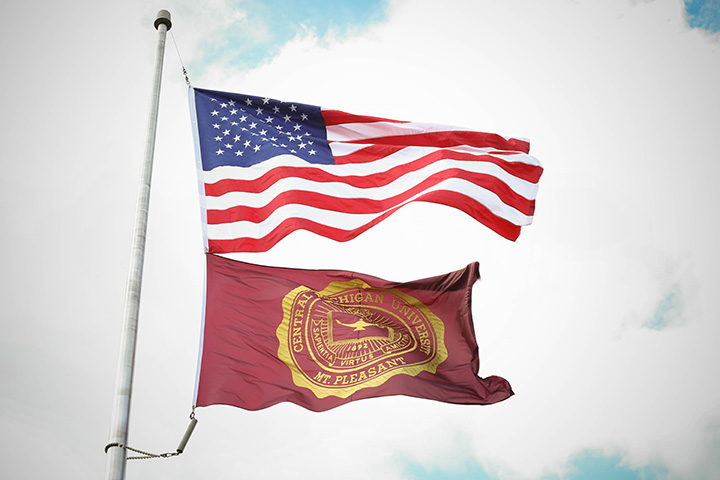 The U.S. flag and CMU flag fly on a flag pole, waving in the breeze.