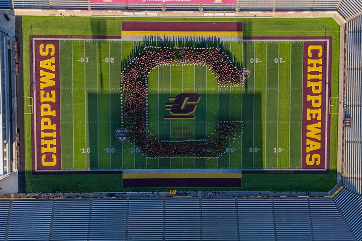 An overhead shot of a football field with people standing in the shape of a C with the word Chippewas visible in both end zones.
