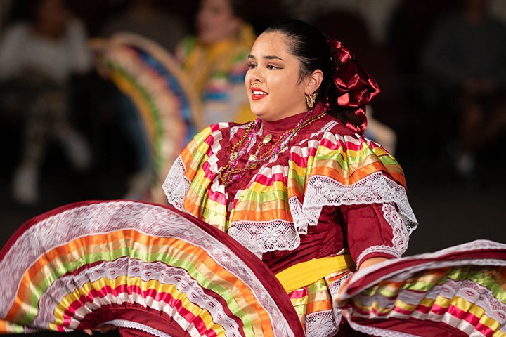 A dancer wears a colorful outfit and dances during a Hispanic Heritage Month celebration.