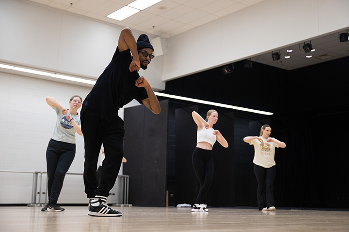Haleem “Stringz” Rasul wears a black outfit and sunglasses in a dance studio while instructing CMU students how to perform the 