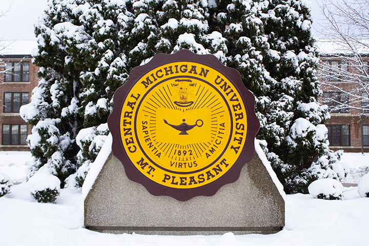 The 6-foot-tall CMU seal stands out in its Gold and Maroon colors, set against snow-covered grass and trees.