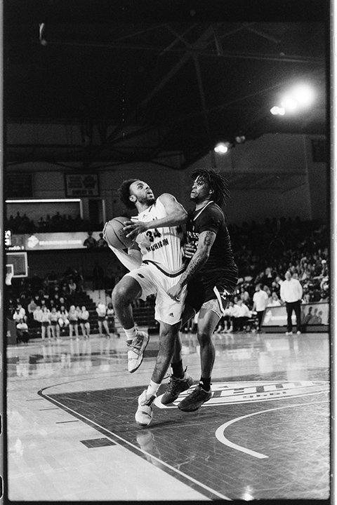 A black and white film image of a CMU basketball player driving to the hoop and taking a shot.