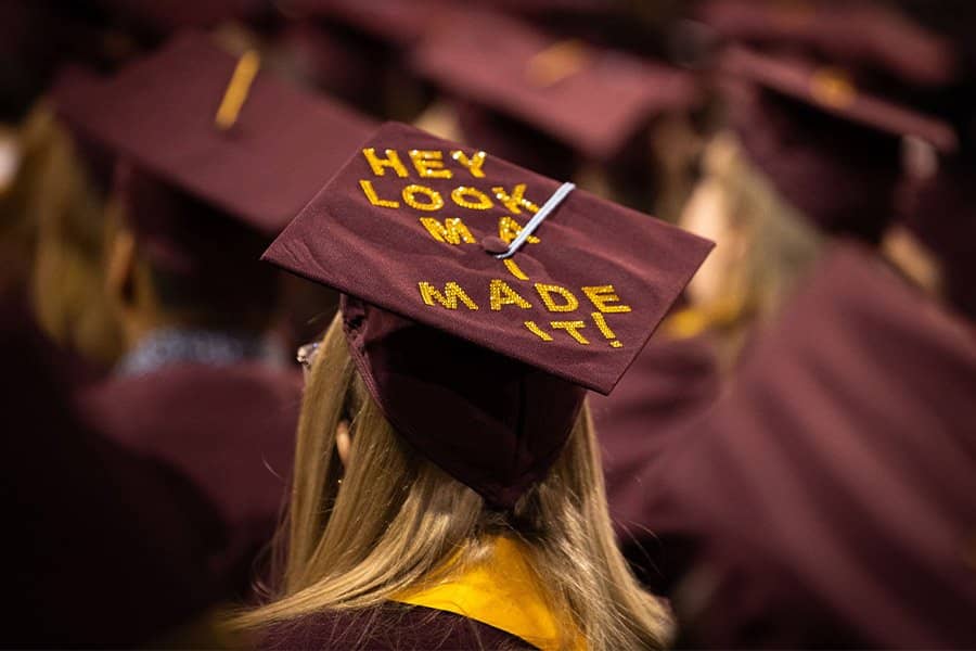 A woman wearing a maroon and gold graduation cap