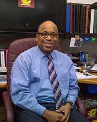 A man in a blue shirt, Stan Shingles, sits in a chair in his office.