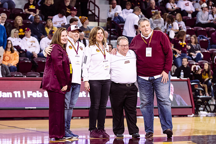 Tim and Sherry Magnusson pose for a photo on the court inside McGuirk Arena with Athletic Director Amy Folan, President Bob Davies and Dean Chris Moberg.