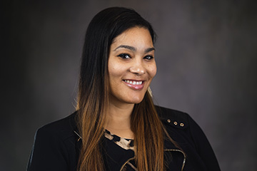 Shawna Patterson-Stephens, CMU vice president for Inclusive Excellence and Belonging, wearing a black jacket and smiling in front of a gray background.