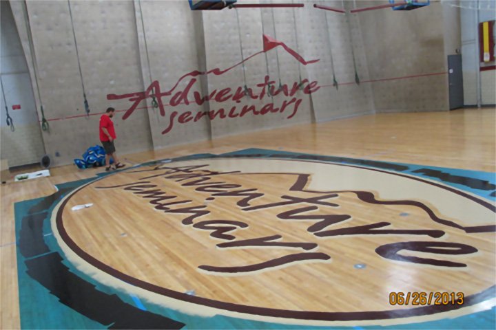 The words Adventure Seminars appear on a wall and a gymnasium floor.