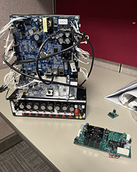 A printed circuit board sits next to a piece of electronic equipment to which it is a component.