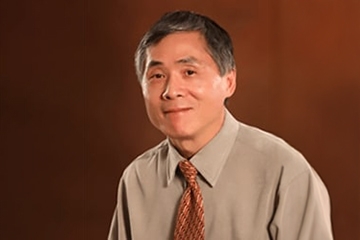 A man wearing a tie in front of a maroon background