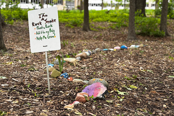 A sign in the ground next to a pile of rocks.