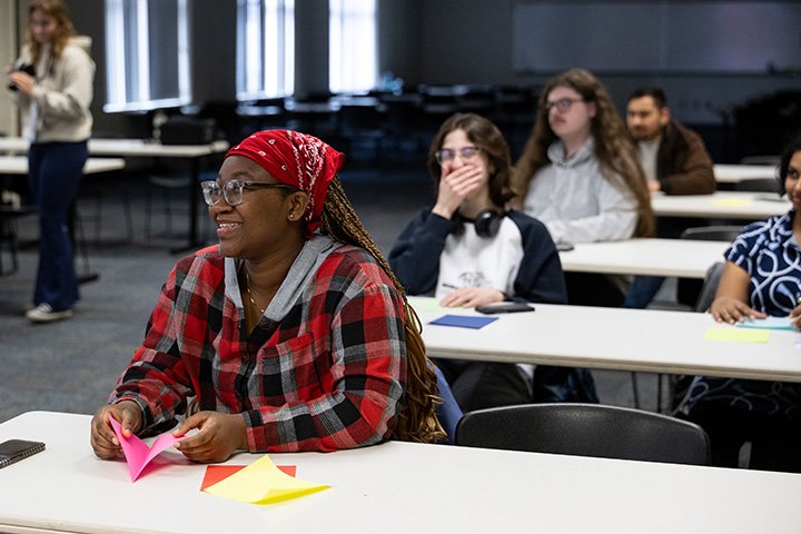 Students sit at tables folding origami.