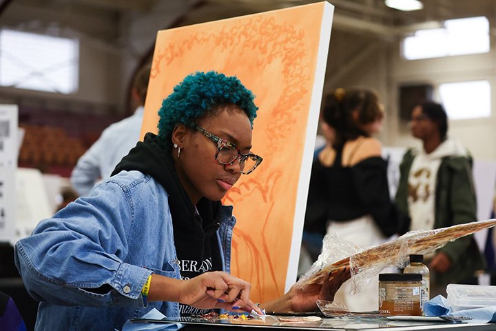 An art student sits at a table painting.