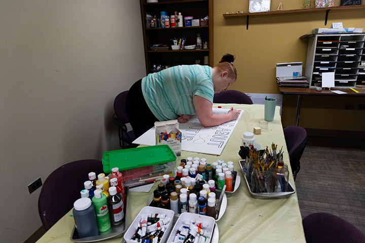 A female college student makes a poster board for autism acceptance.