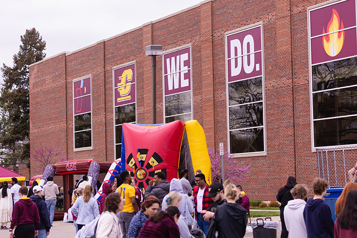 A large group of people stand outside Finch Fieldhouse enjoying fun outdoor activities.