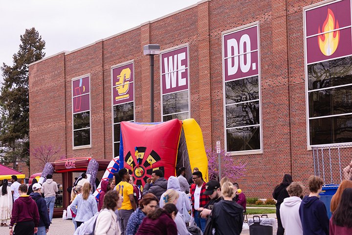 A large group of people stand outside Finch Fieldhouse enjoying fun outdoor activities.