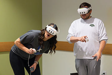 A man and woman wear virtual reality headsets.