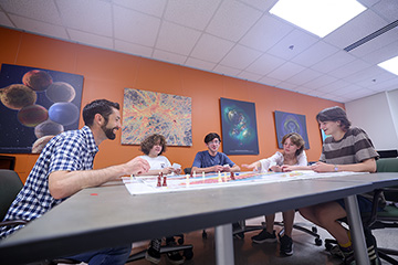 A group of people sitting around a table playing a board game
