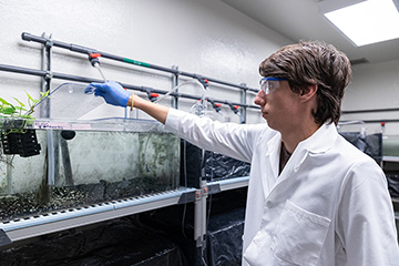 A man wearing goggles and gloves in a lab.