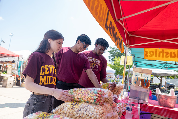 A group of people standing next to a table with bags of popcorn