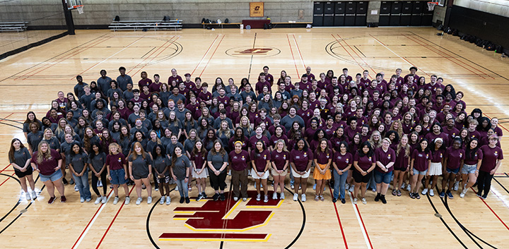 A large group of people pose for a group photo on a basketball court