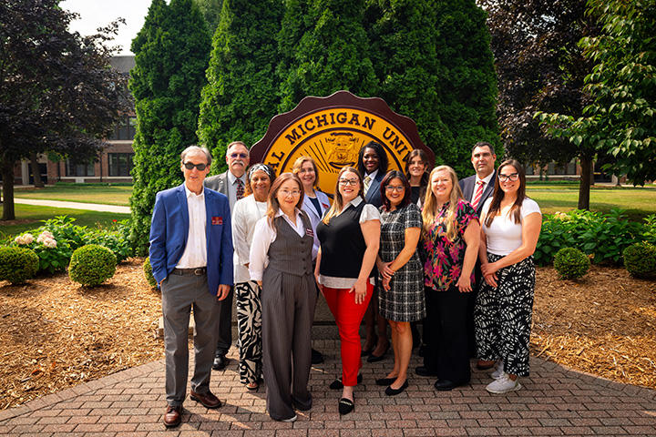 A group of people posing for a photo in front of the CMU seal