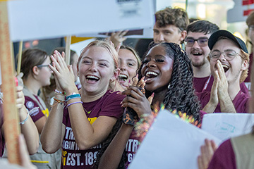 Leadership Safari students clap their hands and smile while walking through a tunnel of people