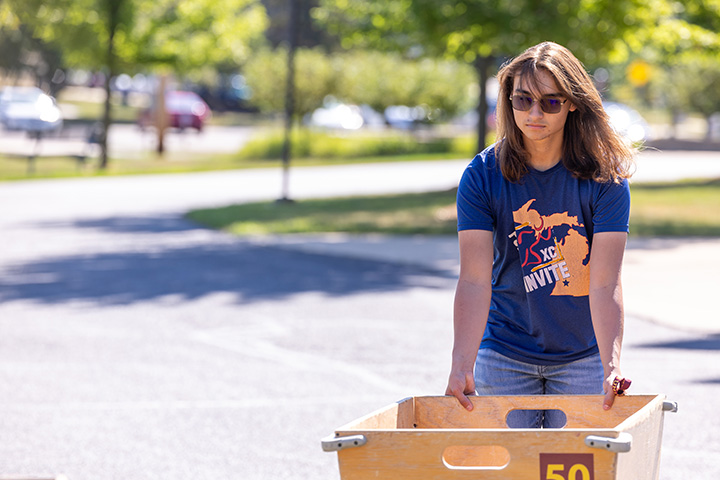 A young woman pushed a wheeled, wooden cart