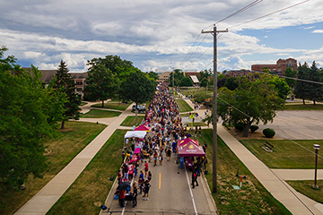 An aerial shot of hundreds of group of people walking down the middle of a street.
