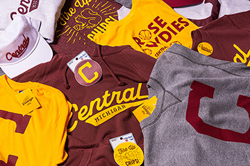 A pile of Central Michigan University clothes and hats on a table