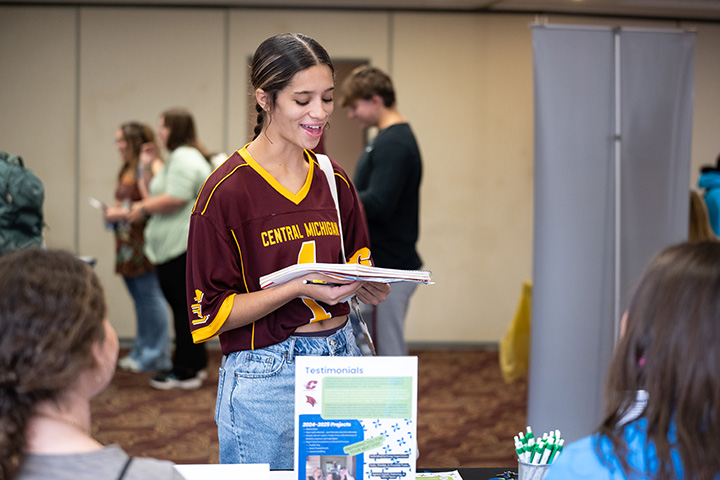 A woman wearing a football jersey holding a stack of papers in a room