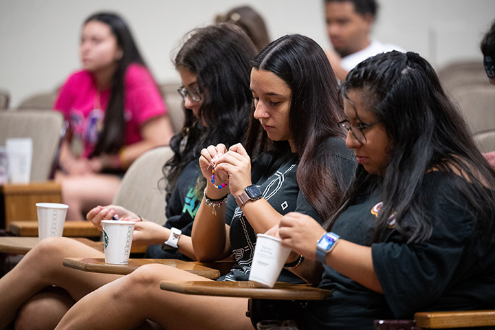 A group of women sitting in chairs making bracelets