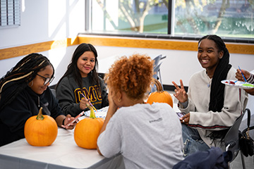 A group of people sitting around a table with pumpkins