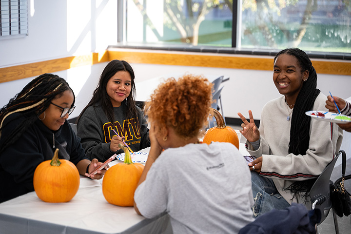 A group of people sitting around a table with pumpkins