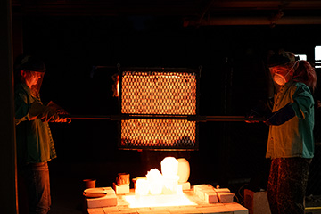 Two people stand around a blazing kiln fire