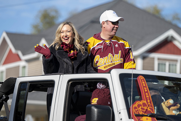 President MacKinnon and first lady Leanne ride in a white Jeep.