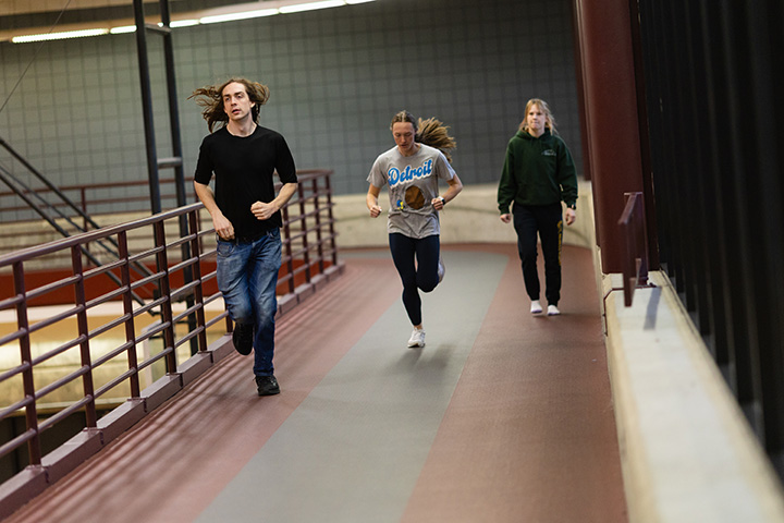 A group of people running on an indoor track.