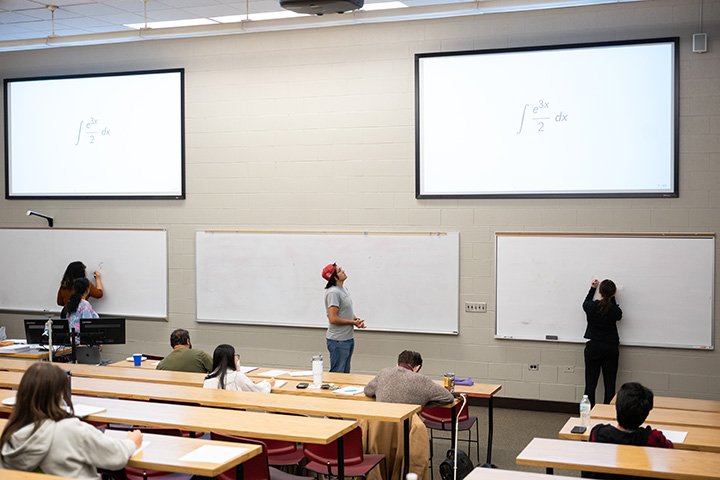 People standing in front of a whiteboard with math equations written on it