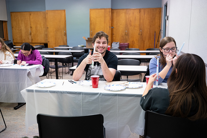 A group of people sitting at a table making decorative candles.